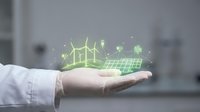Professional hand presenting holographic green energy icons including wind turbines and solar panels in modern office environment for sustainable technology concepts.
