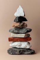 Stacked stones in various textures and colors balanced vertically on neutral background, symbolizing stability, balance, and harmony for wellness, meditation, and mindfulness design projects.