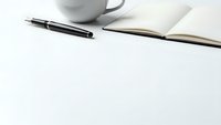 Minimalist workspace with black pen, open notebook and white coffee mug on clean desk surface for business planning and productivity concepts.