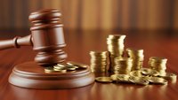 Wooden judge gavel with golden coins on desk representing legal fees, court costs, financial litigation, bankruptcy proceedings, and justice system expenses.