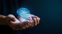 Hands holding glowing digital brain with neural network connections representing artificial intelligence, machine learning and cognitive technology innovation.