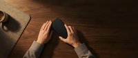 Businessman hands protecting black paper house model on wooden desk symbolizing home insurance and real estate security concept.