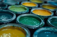 Open paint cans showing vibrant yellow and green colors with glossy wet texture, arranged in rows creating depth and artistic composition for renovation projects.