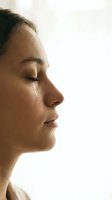Young woman with closed eyes and tear on cheek in profile view showing emotional moment with soft natural lighting for mental health concepts.