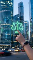 Hand touching holographic justice scales interface with digital people icons against modern city skyline at dusk for legal technology concepts.