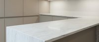 Modern kitchen interior with white marble countertop and beige cabinets featuring clean minimalist design for contemporary home renovation projects.