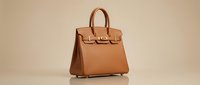 Tan leather handbag with structured silhouette and dual handles, isolated on neutral background for fashion retail, e-commerce, and accessory design use.
