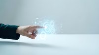 Hand of a Caucasian male professional in dark business suit pointing at glowing digital gear and technology icons, representing innovation, engineering, and industrial solutions.