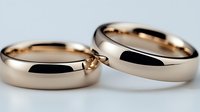 Elegant rose gold wedding bands on light background, classic polished finish rings symbolizing marriage commitment and eternal love, close-up macro photography.