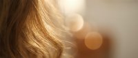 Golden blonde hair strands catching warm sunlight with soft bokeh background creating dreamy atmosphere for beauty and haircare concepts.