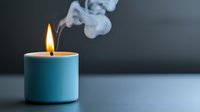 Blue candle burning with flame and white smoke rising against dark background for relaxation and aromatherapy concepts.