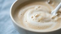 Creamy coffee with milk foam swirl in white ceramic cup, morning beverage with latte art pattern for cafe menu and coffee shop advertising materials.