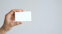 Hand holding blank white business card against neutral background, suitable for branding, corporate identity, and marketing mockup presentations.