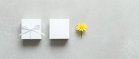 White gift box with ribbon, blank card and yellow daisy flower arranged on neutral background for greeting cards, invitations and celebration designs.