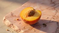 Sliced peach with pit on marble surface in warm sunlight, suitable for food photography, culinary blogs, recipe websites, and healthy eating content.