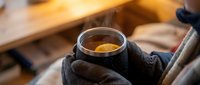 Worker in dark gloves holding glass jar with golden honey, ideal for food production, beekeeping, and agricultural marketing materials.