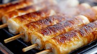 Grilled Japanese yakitori skewers with glazed white meat on wooden sticks, caramelized surface and juicy texture, cooking on hot barbecue grill with smoke.
