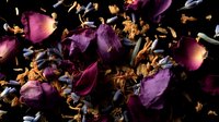 Dried purple rose petals and golden leaves scattered on dark background creating romantic and dramatic composition. Floral decay shows passage of time.