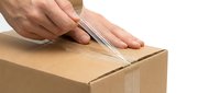 Caucasian male hands using clear packing tape to seal a cardboard box during shipping and delivery preparation process.