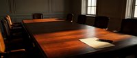 Elegant wooden conference table in professional boardroom with leather chairs and natural lighting for corporate meetings and business presentations.