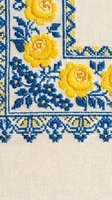 Traditional Ukrainian embroidery with yellow roses and blue flowers on linen fabric. Folk art needlework pattern for cultural textile design projects.