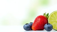 Fresh mixed berries with lime slice on white background for healthy eating and nutrition concepts.