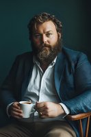 Confident bearded businessman in blue suit jacket holding coffee cup, professional portrait with dramatic lighting for corporate and lifestyle concepts.
