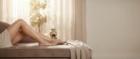 Woman relaxing on massage table in spa wellness center with soft natural lighting and peaceful atmosphere for beauty treatments and self-care.