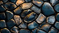 Dark cobblestone texture with golden sunlight highlights creating dramatic shadows on wet stone surface, abstract pattern of ancient paving blocks.