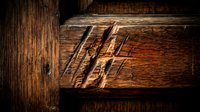 Weathered wooden beam with carved Roman numerals showing rustic craftsmanship and aged texture for construction and carpentry projects.