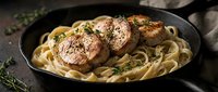 Pan-seared scallops with creamy pasta and fresh herbs in cast iron skillet. Gourmet seafood dinner with fettuccine noodles for restaurant menu design.
