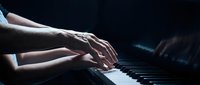 Pianist hands playing piano keys in dramatic lighting. Professional musician performing classical music with elegant finger technique on keyboard instrument.