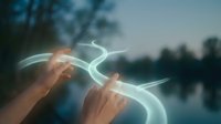 Hands holding glowing neon light trails against blurred lake and forest backdrop, representing energy, magic, and digital connection for creative and tech projects.
