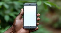 African American hand holding modern smartphone with blank white screen against blurred green natural background, mockup for app or web design presentation.