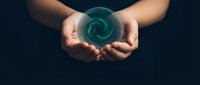 Hands holding glowing turquoise energy spiral orb against dark background. Concept for healing, meditation, spiritual power and mystical forces.