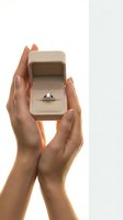 Woman hands holding open engagement ring box with diamond ring on white background for wedding proposal and marriage concept.