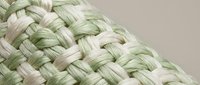 Close-up of woven natural fiber texture with green and beige strands creating intricate basket weave pattern for craft and textile design projects.