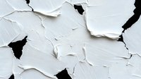 Cracked and peeling white paint texture on wall surface showing layers of deterioration and black gaps, creating abstract pattern of decay and weathering.