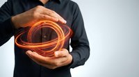 Business professional protecting glowing orange digital sphere with hands representing cybersecurity data protection and technology innovation concepts.