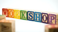 Colorful wooden alphabet blocks spelling WORKSHOP arranged in row on white background. Educational toy letters for learning and creativity projects.