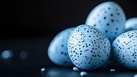Speckled blue eggs with black dots arranged on dark surface for Easter decoration and spring holiday design projects.
