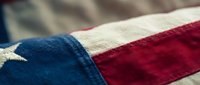 Close-up macro view of vintage American flag fabric showing detailed textile weave and patriotic red white blue colors for Memorial Day Independence Day designs.