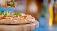 Olive oil pouring from bottle onto fresh homemade pizza with melted cheese and toppings on wooden cutting board, close-up view with soft background blur.
