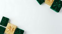 Wrapped gift boxes in emerald green and gold with ribbon bows arranged on white background, overhead view for holiday, celebration, and seasonal marketing materials.