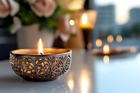Ornate decorative candle with intricate metallic pattern burning brightly, surrounded by blurred roses and glowing candles, creating ambient lighting for home decor, events, and relaxation settings.