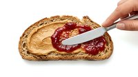 Croissant spread with peanut butter and red jam on white background, isolated for bakery, food packaging, and culinary design projects.
