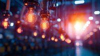 Vintage Edison light bulbs hanging from ceiling with warm orange glow against blurred bokeh background creating cozy atmospheric lighting in modern interior space.