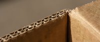 Corrugated cardboard texture showing detailed fluted structure and brown kraft paper layers for packaging and shipping materials.