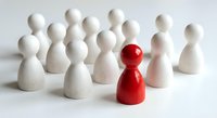 Red wooden pawn figure standing out among white pawns on clean background. Leadership, uniqueness, and individuality concept for business presentations.