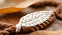 Nautical rope knots on wooden deck surface with brown and white twisted fibers creating maritime sailing pattern for marine adventure designs.